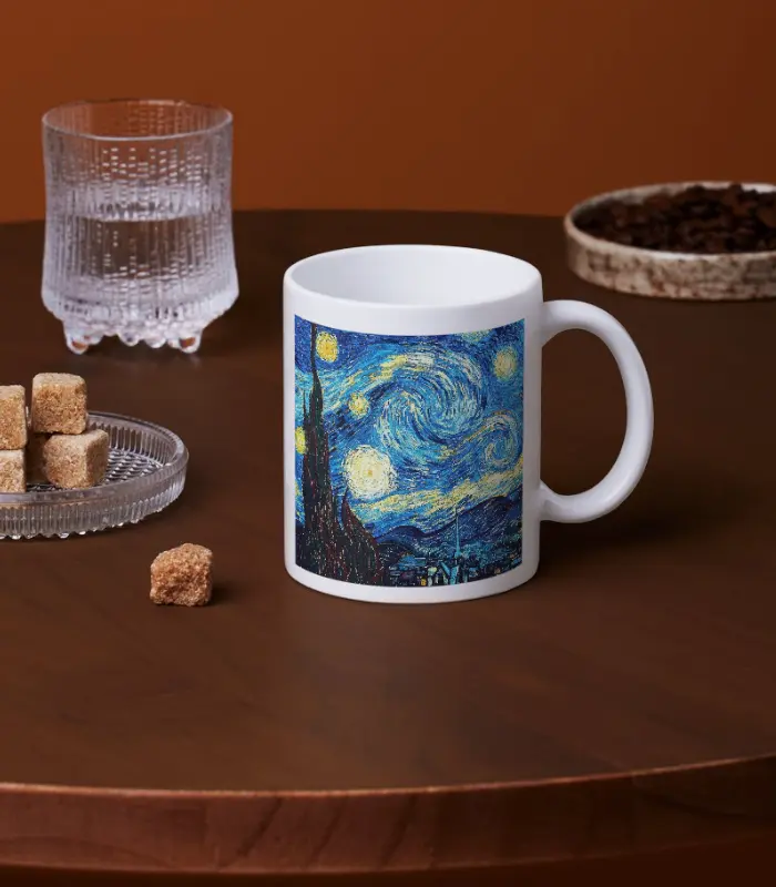 Kahverengi bir masada "Van Gogh, Yıldızlı Gece Tasarımlı Kupa Bardak" yanında bir bardak su, bir tabak şeker küpü ve bir tabak kahve çekirdeği ile birlikte sergileniyor.